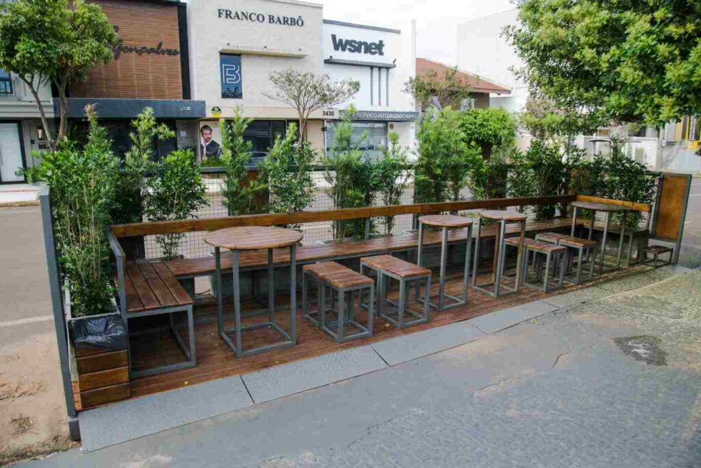Estruturas com bancos e mesas na pista de estacionamento de ruas